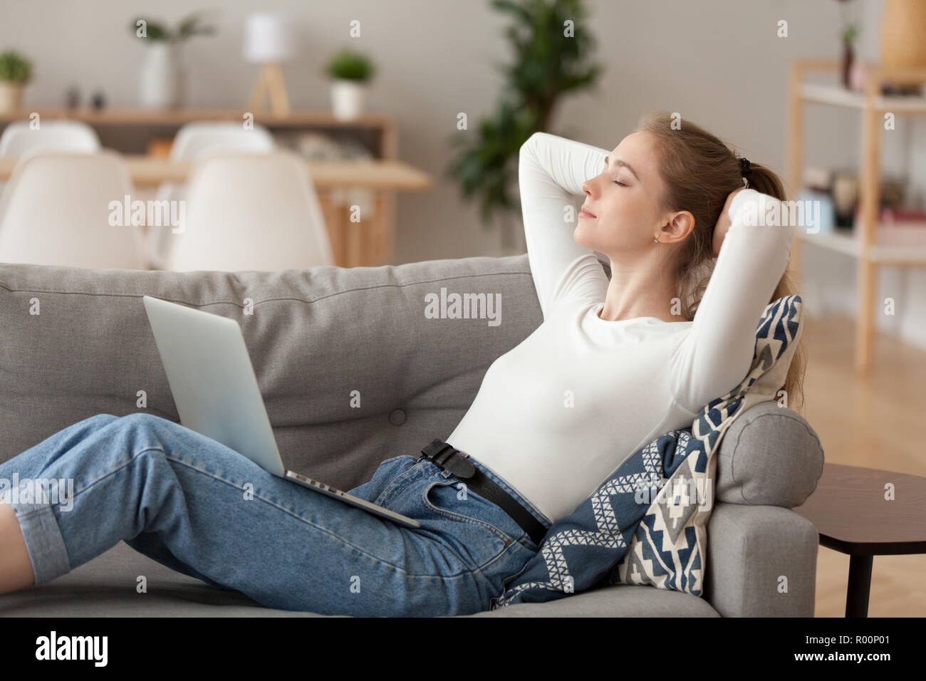 Attractive woman with computer lying on couch Stock Photo