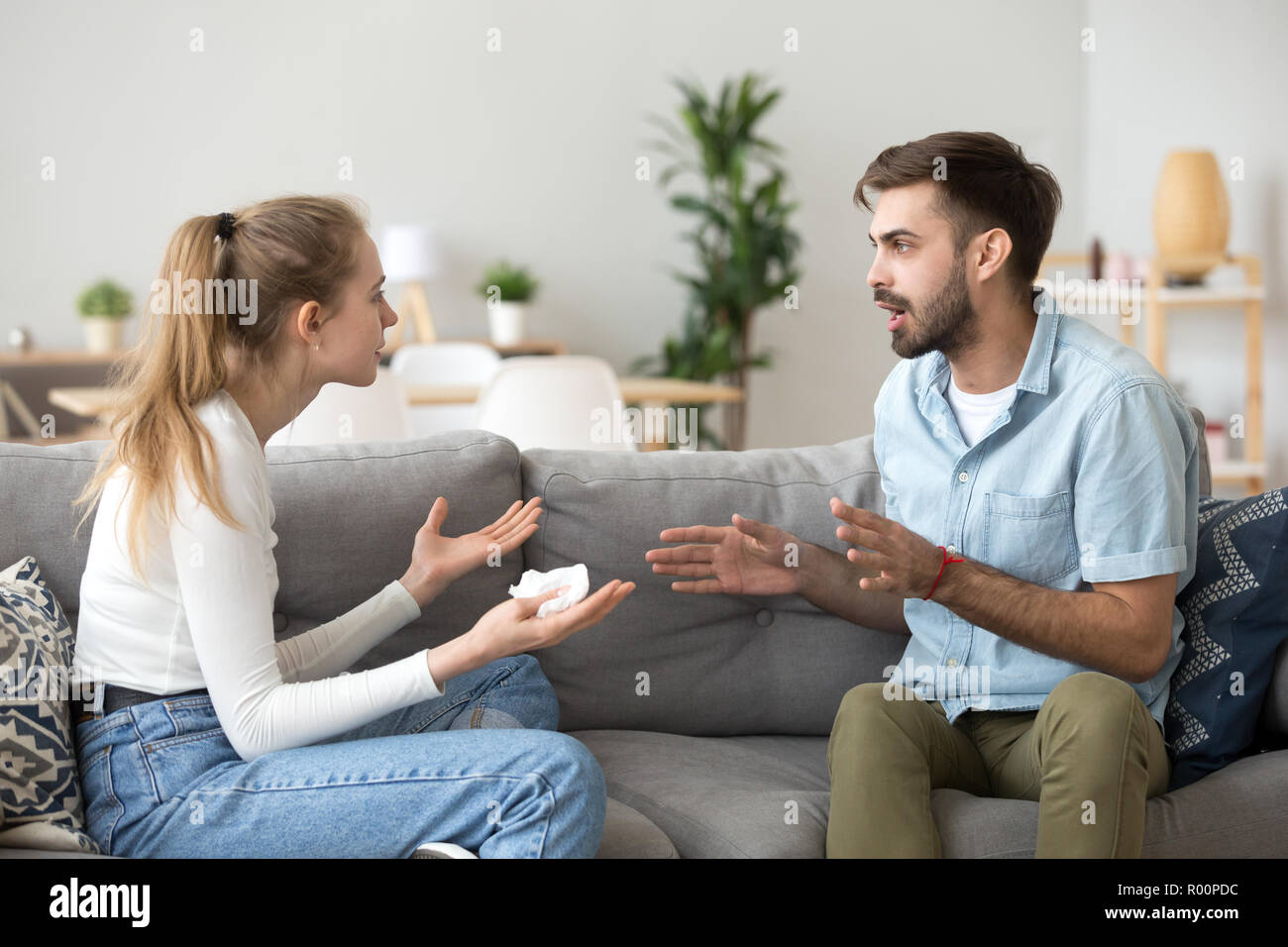 Coupe emotionally arguing sitting on couch at home Stock Photo - Alamy