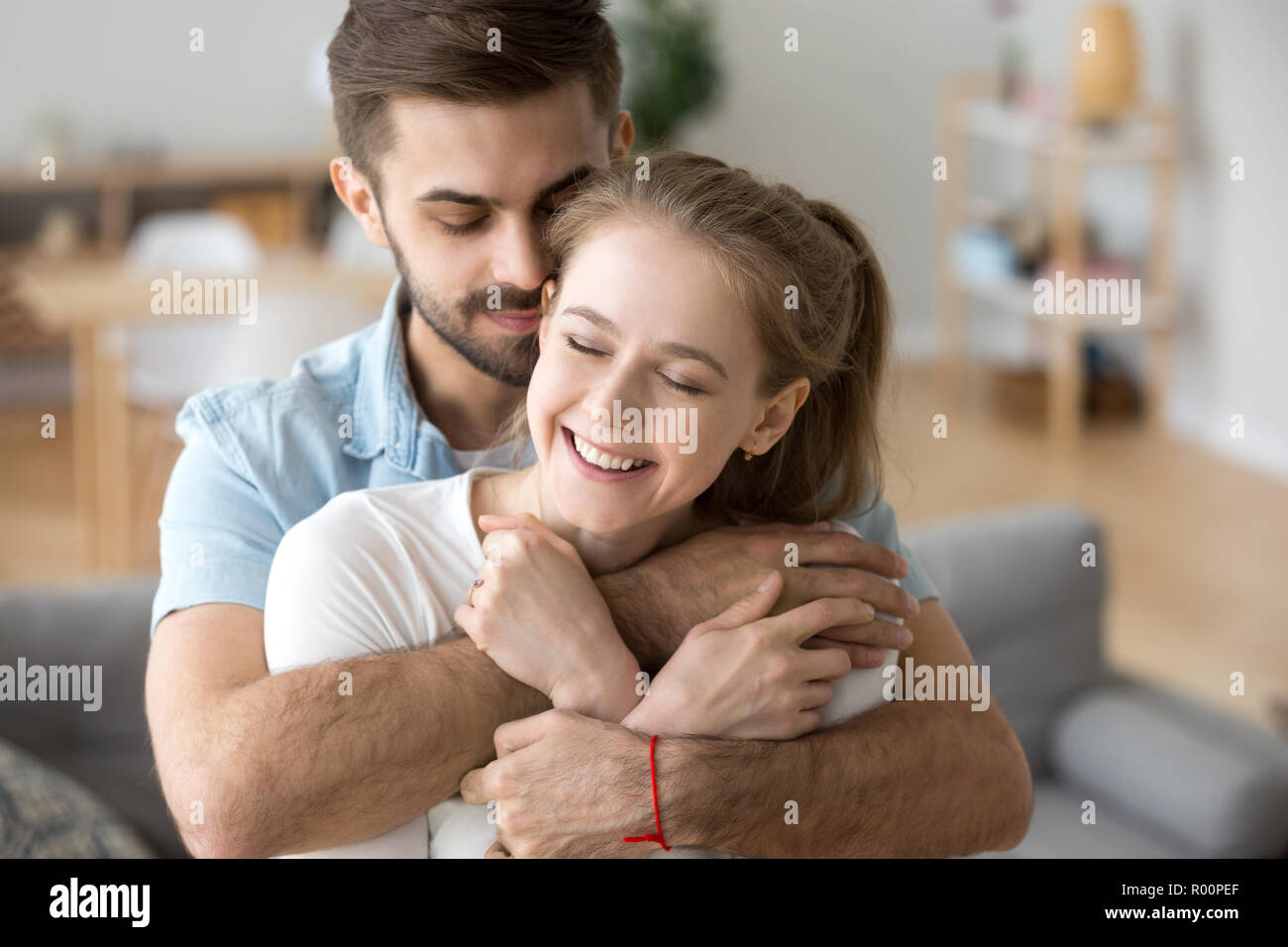 Attractive millennial happy married couple embracing indoors Stock Photo