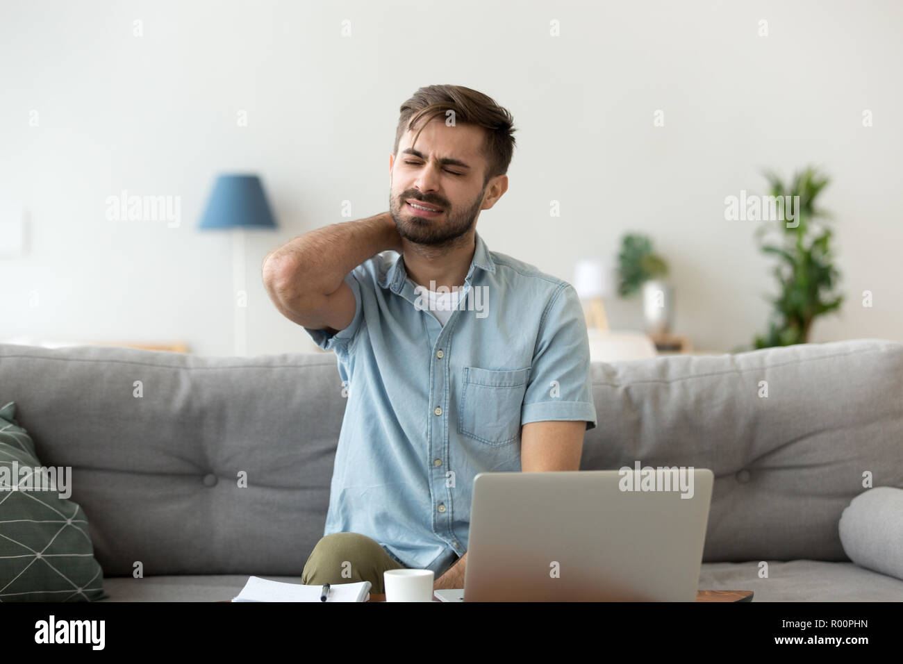 Man having neck pain sitting working at home Stock Photo