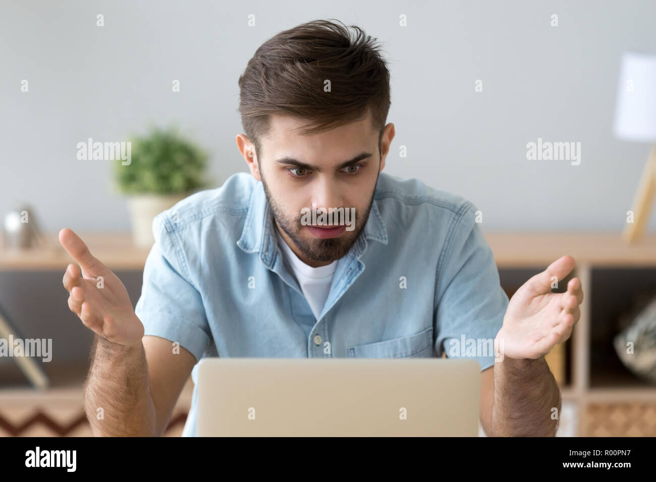 Frustrated man looking at computer screen sitting at the desk Stock Photo