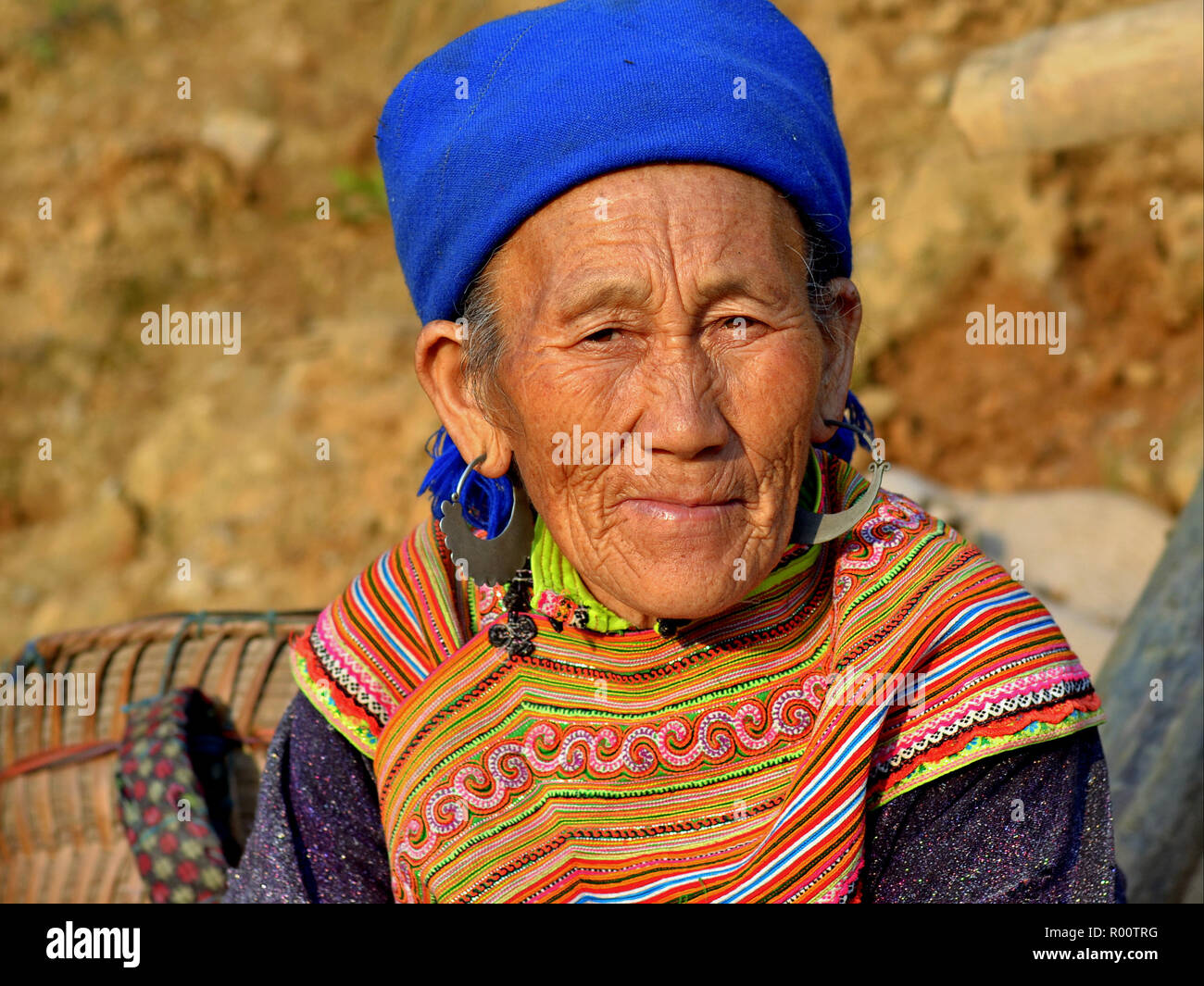 Old Vietnamese Flower H’mong hill-tribe market woman with large silver earrings in colourful traditional attire. Stock Photo