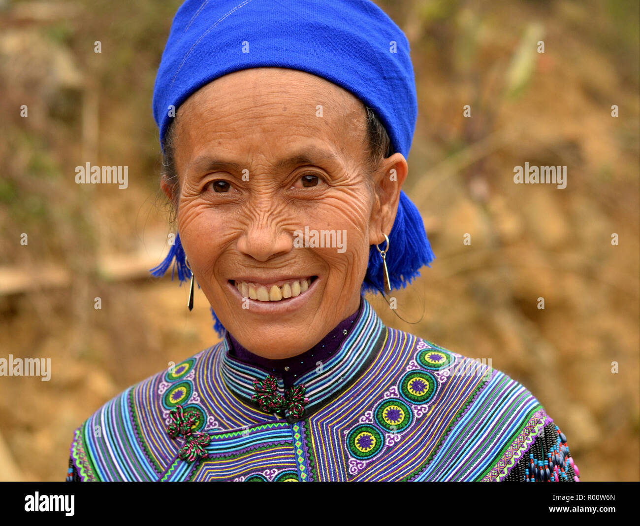 Elderly Vietnamese Blue H’mong woman with embroidered traditional H’mong attire and blue headscarf. Stock Photo