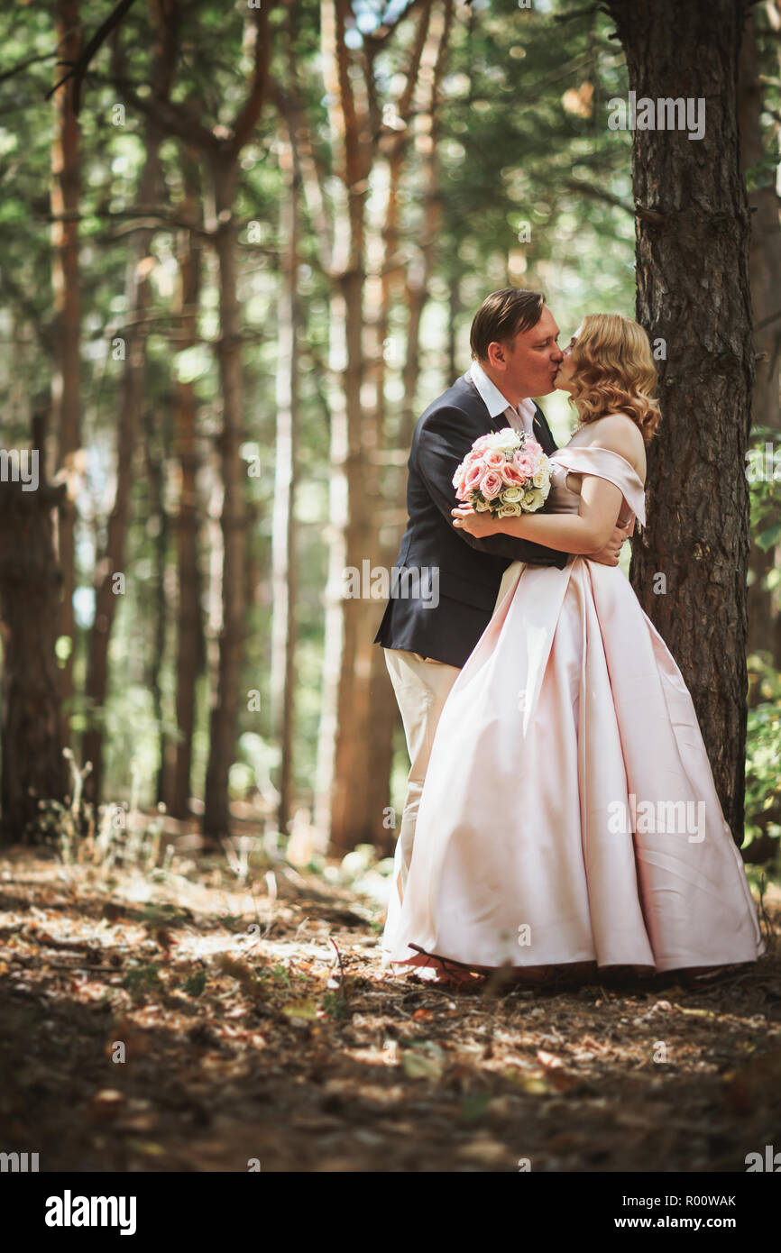 bride and groom kiss on the background of trees and forest Stock Photo ...