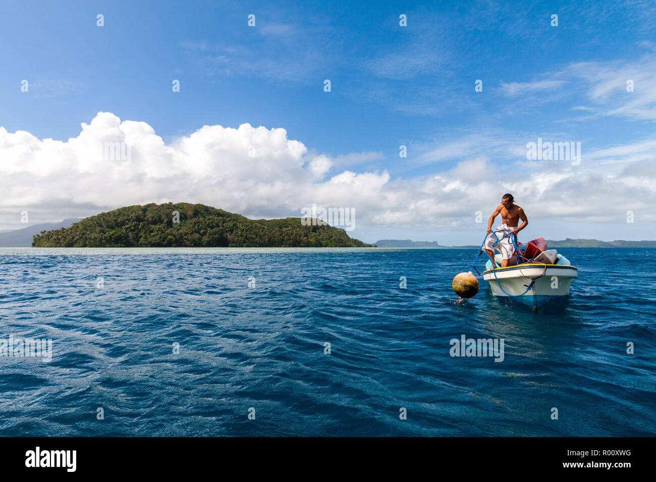 Local Micronesian man in a fishing boat pulls a buoy out of the water near Nan Madol, Pohnpei island, Federated States of Micronesia. Stock Photo