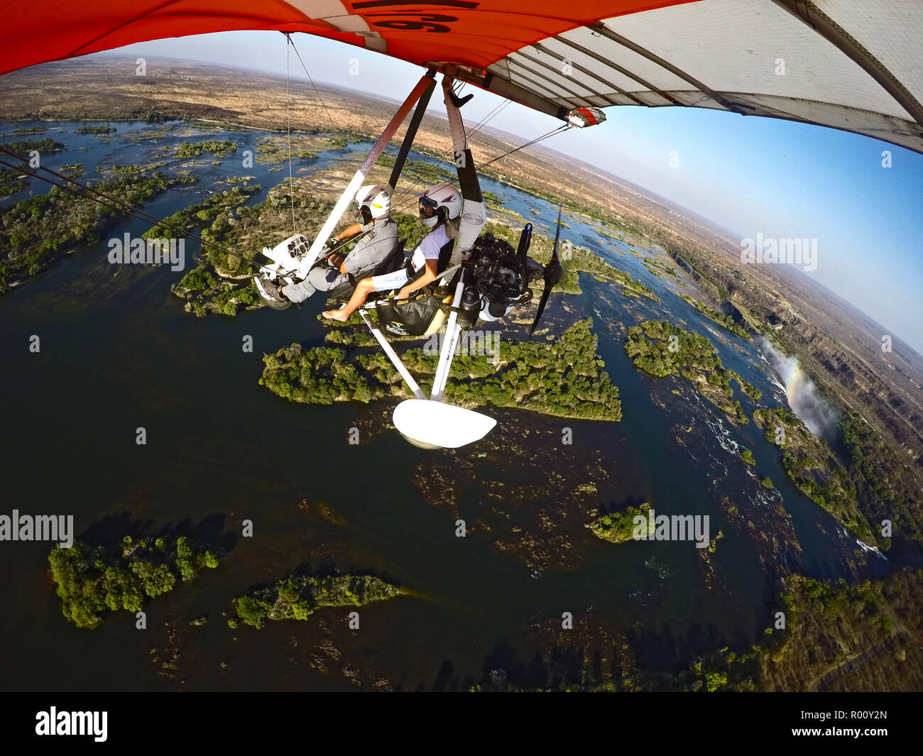 Microlight flight takes female passenger on the flight of a lifetime over the turbulent waterfalls of Victoria Falls on the border of Zambia and Zimba Stock Photo