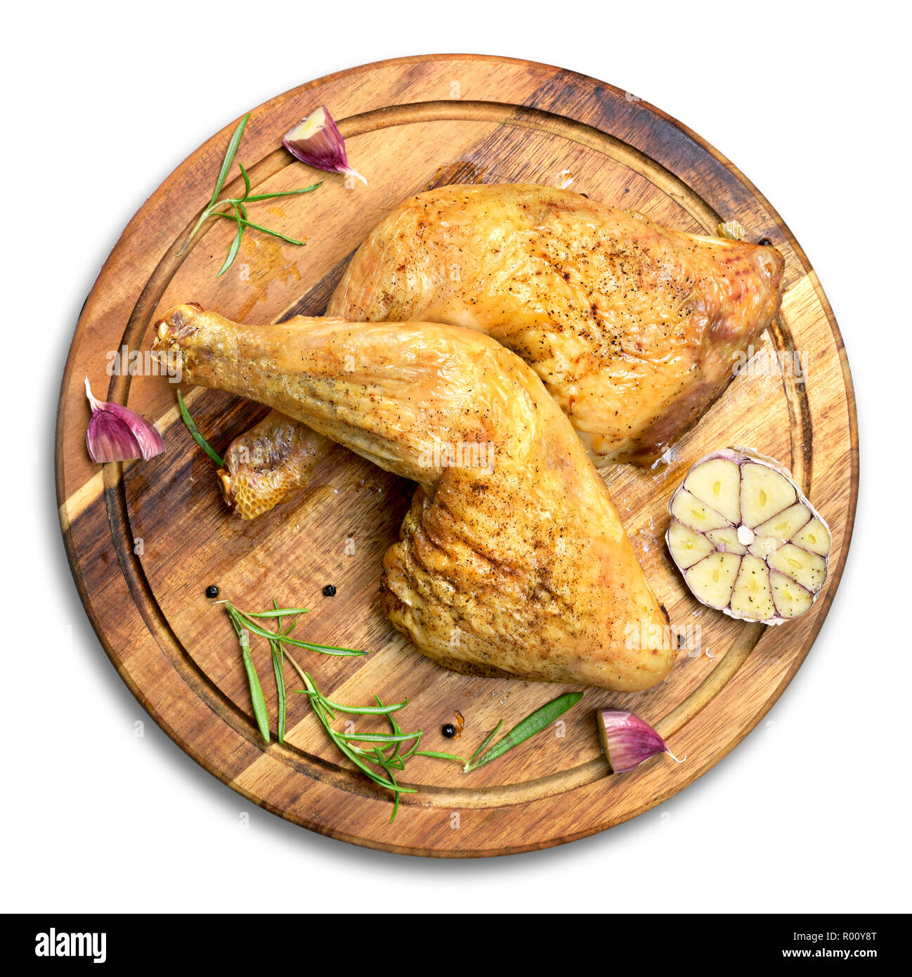 Delicious roast chicken legs or chicken drumsticks on a wooden cutting board. High angle view and fresh rosemary and garlic. Isolated on white backgro Stock Photo