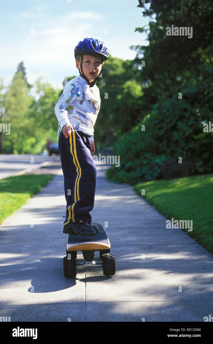 Young boy wearing a cycle helmet while skateboarding on a suburban
