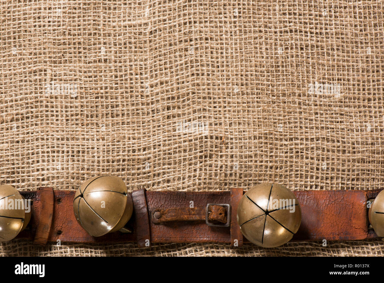 Antique sleigh bells and leather harness on burlap. Stock Photo