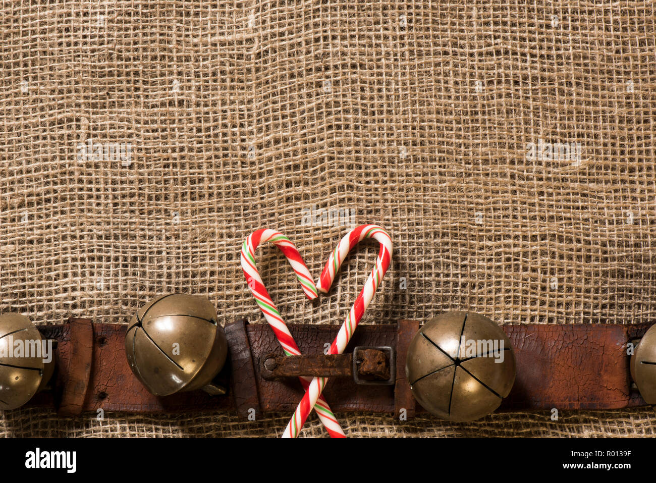 Antique sleigh bells and leather harness on burlap. Stock Photo