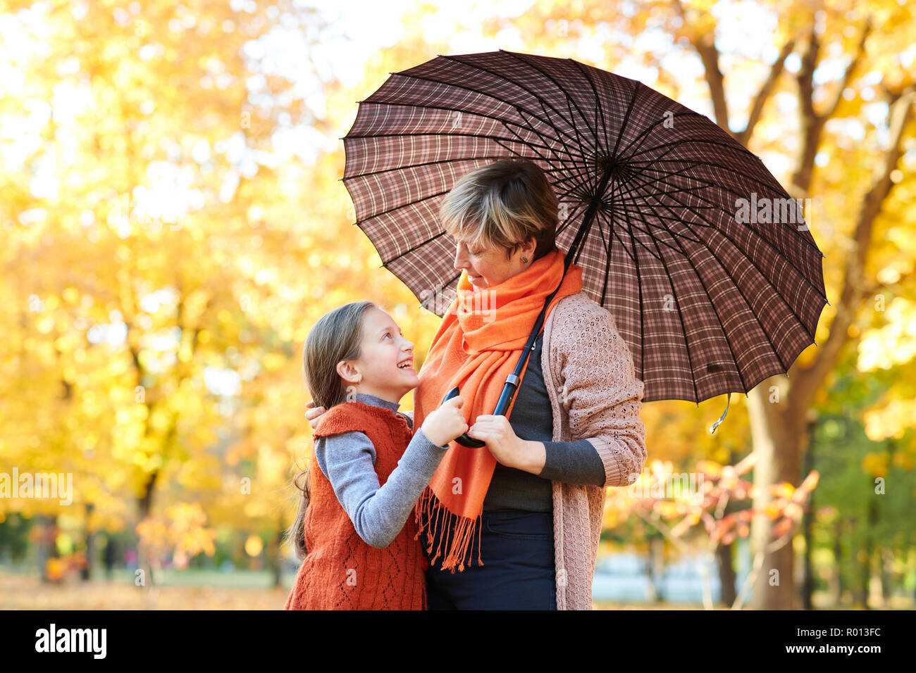 Mother and daughter are in autumn city park. Peoples are posing under ...