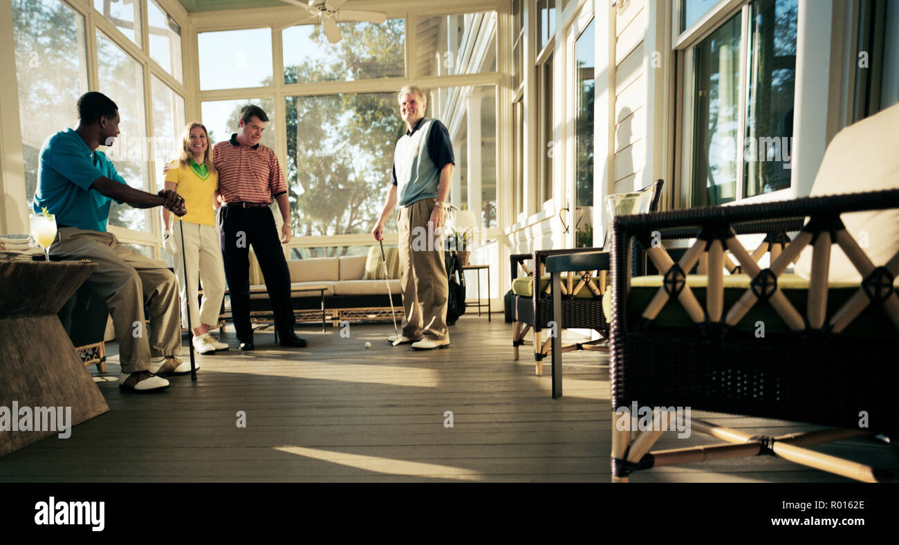 Friends practising golf in a conservatory Stock Photo