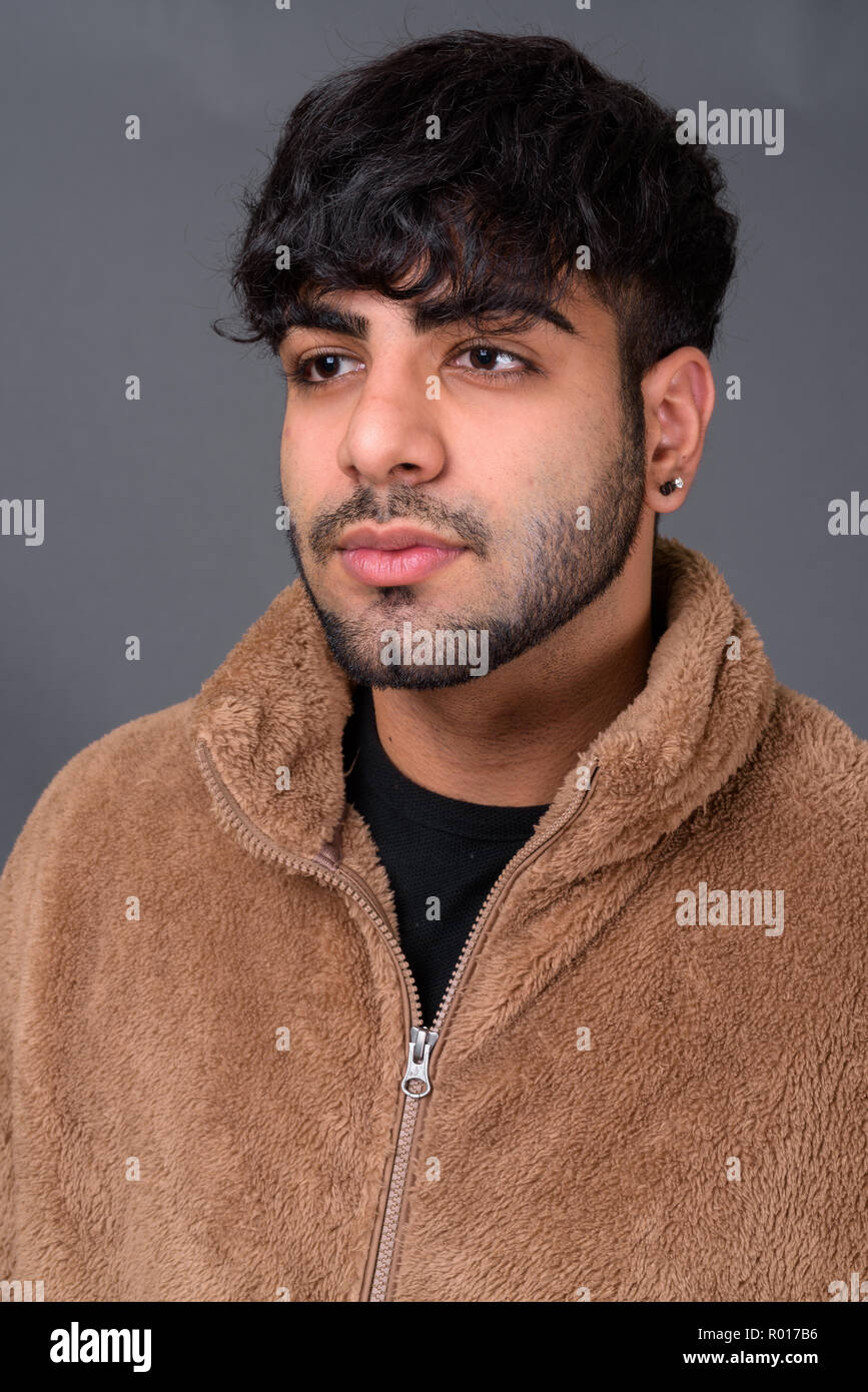 Young handsome Indian man against gray background Stock Photo