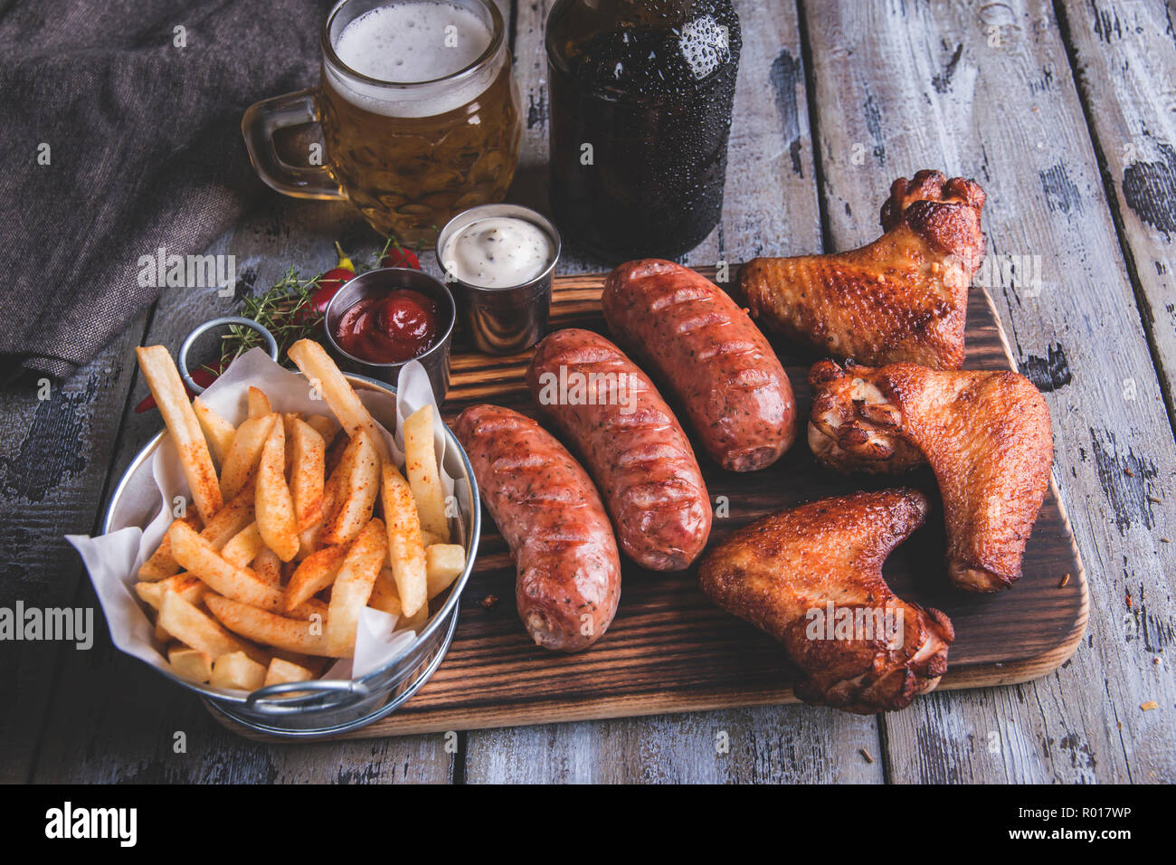 Fried chicken wings,grilled sausages, french fries, nuts, white and red sauce. food to beer Stock Photo