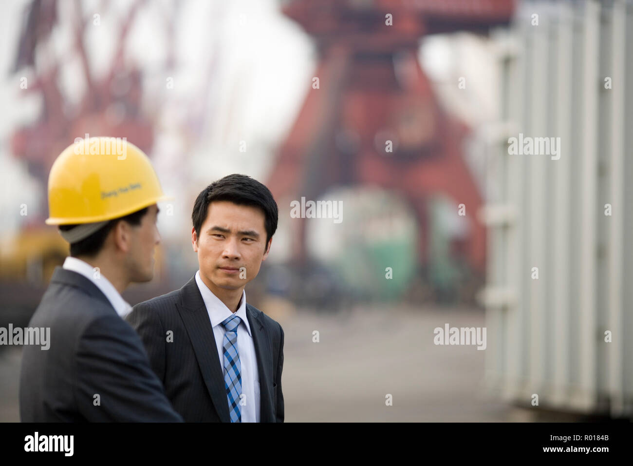 Young adult businessman standing with a mid-adult colleague on a shipping dock. Stock Photo