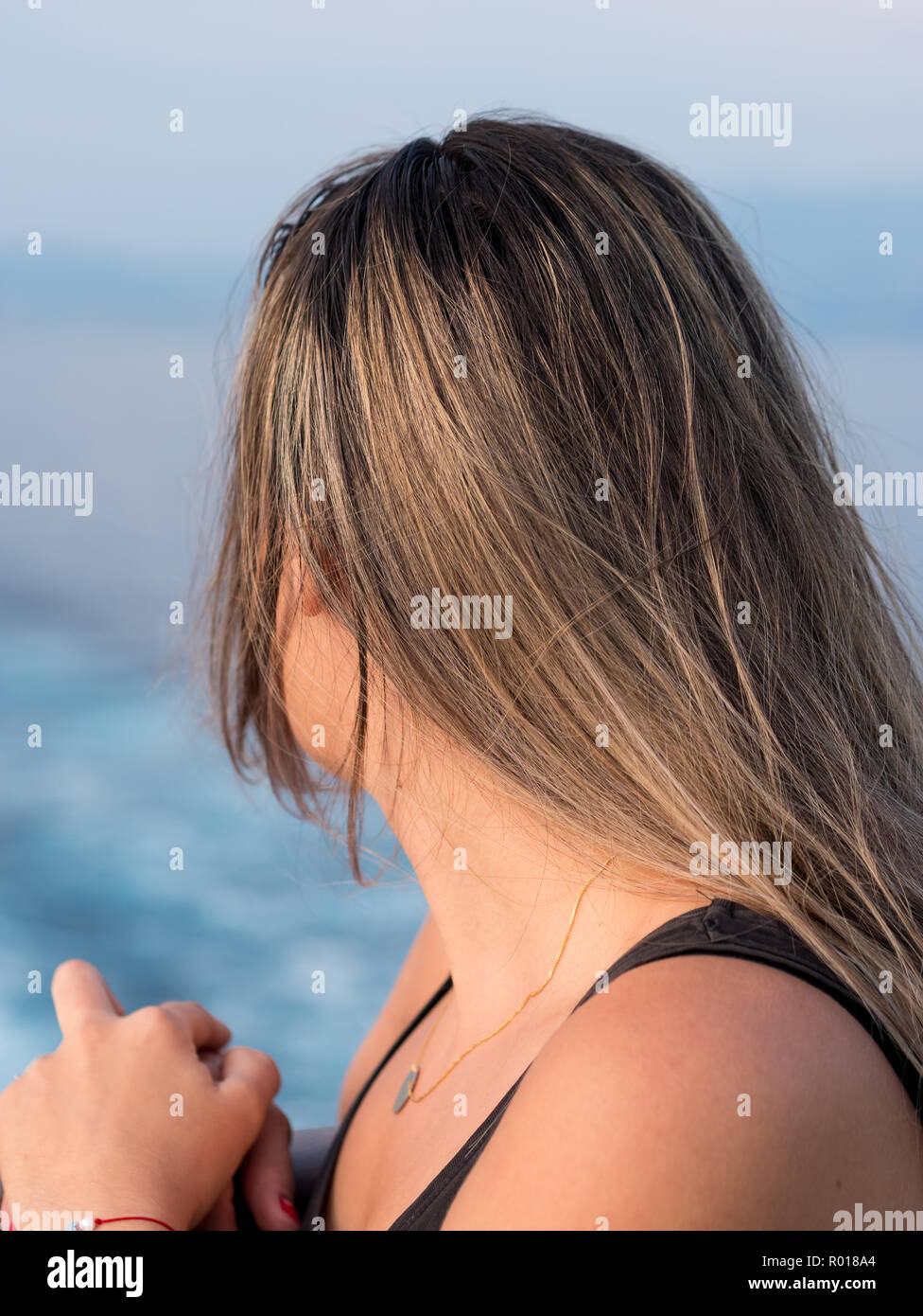 Caucasian woman with long hair on boat from the back looking at the sea ...