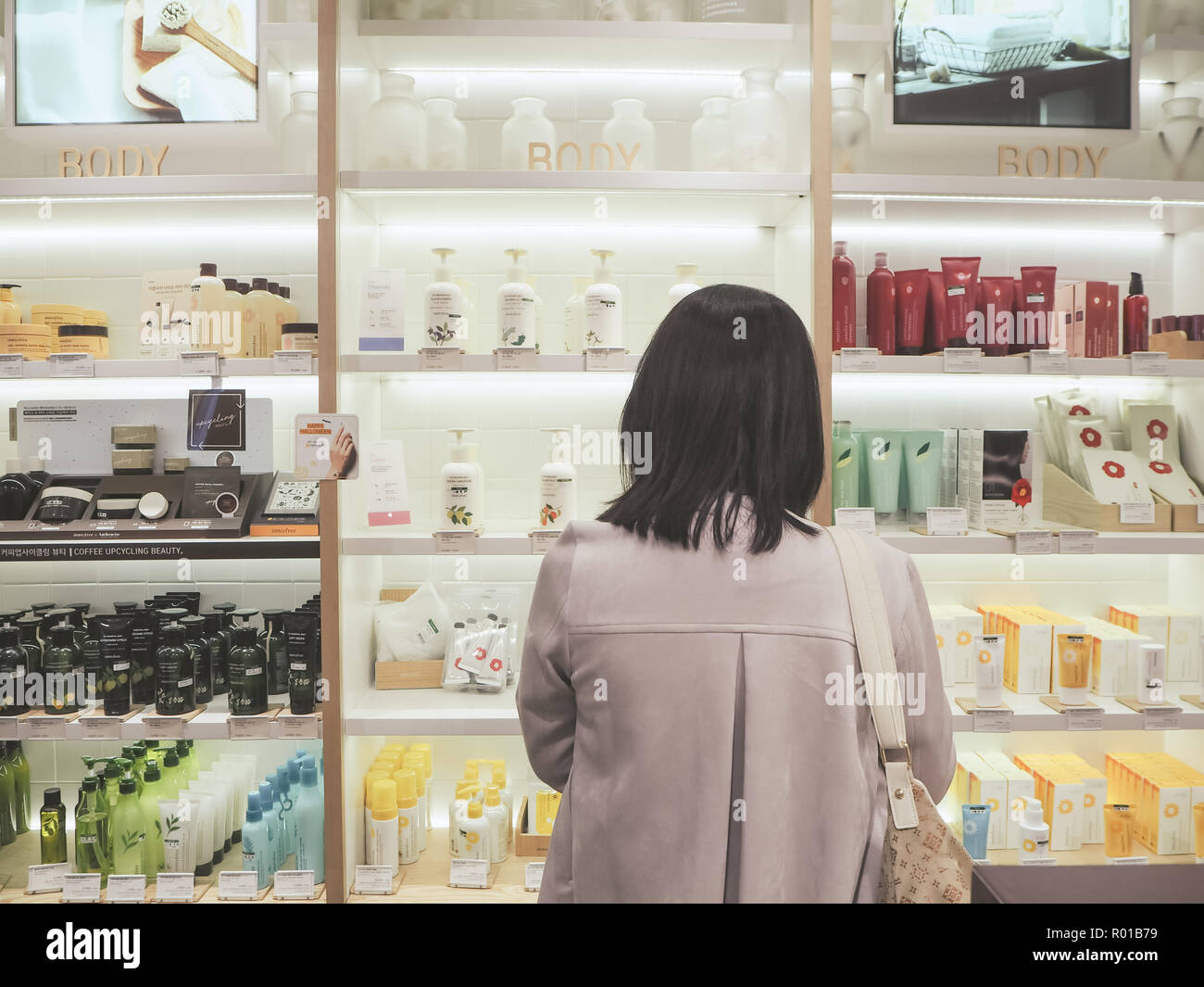 October 2018 - Seoul, SOuth Korea: Young Asian woman standing in front of a shelf with skincare products of the South Korean brand Innisfree Stock Photo