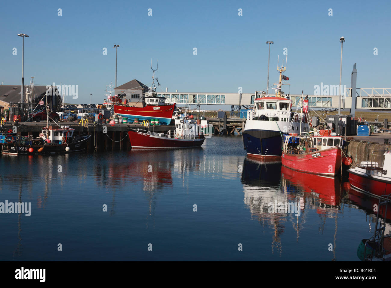 The harbour in Stromness, Orkney with fishing boats, the Hoy/Graemsay ferry centre right, and a ferry passenger footbridge Stock Photo