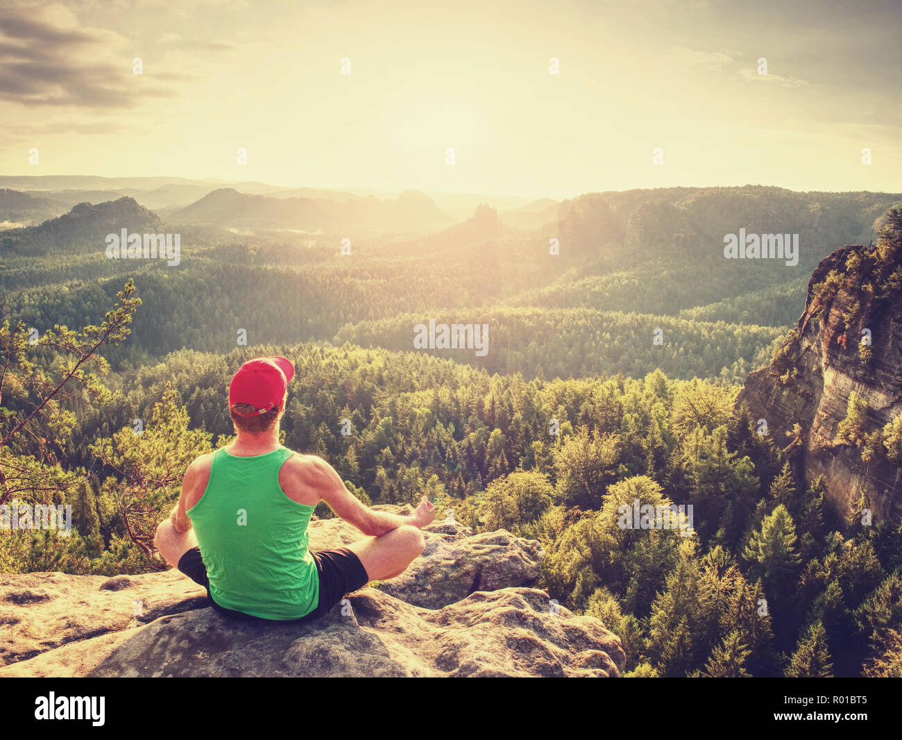 Meditating yoga position on the top of a mountains. Man meditate on mountain at sunrise Stock Photo
