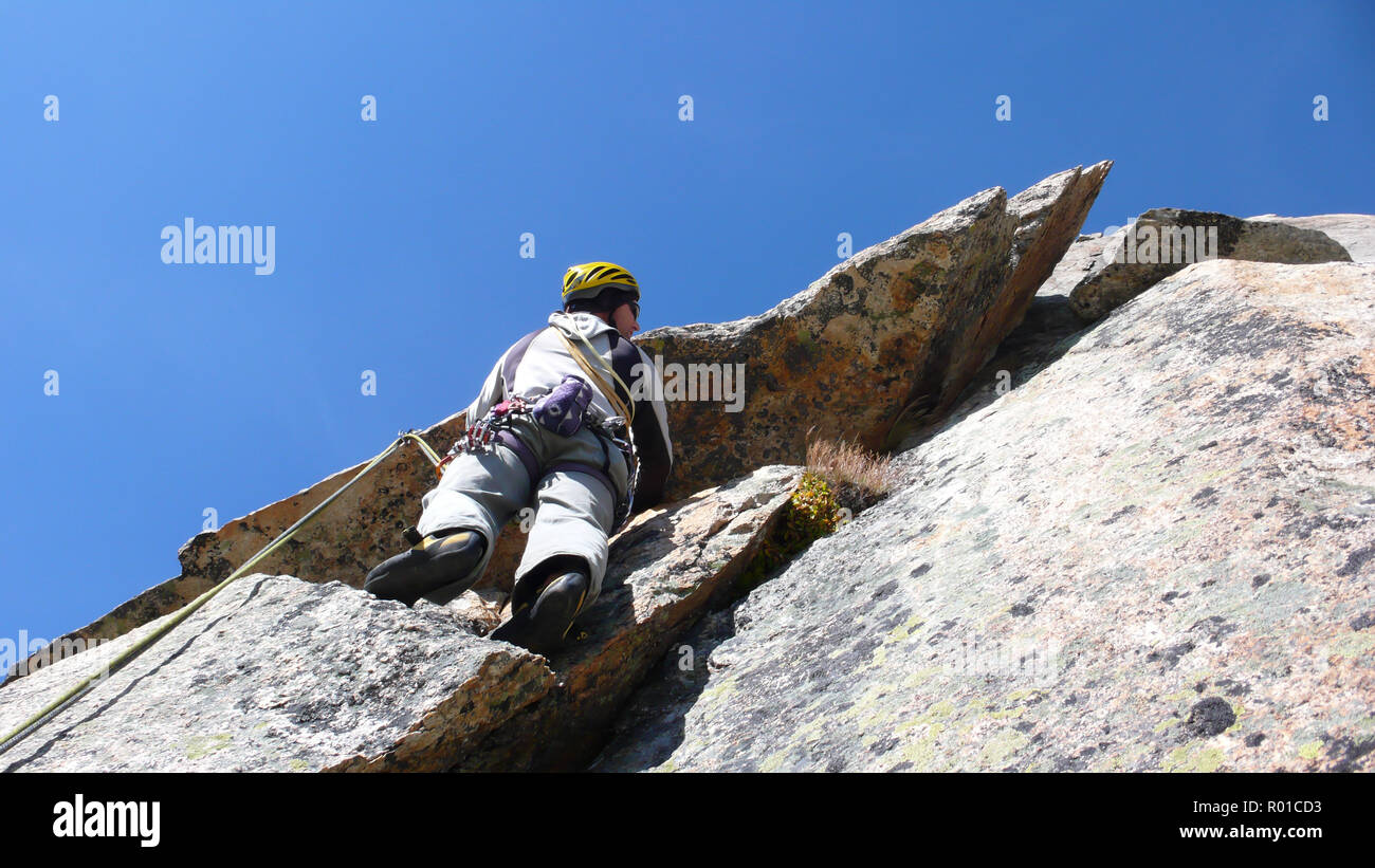mountain guide rock climber on a steep granite route in the Alps of Switzerland on a beautiful