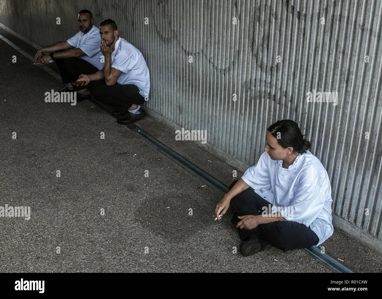 cigarette break for kitchen staff crouching in street Stock Photo