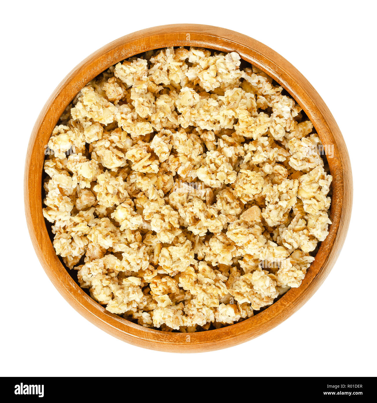 Crunchy granola in wooden bowl. Crispy cereals, made of rolled and toasted whole grain oat flakes and honey. Breakfast and snack food. Stock Photo