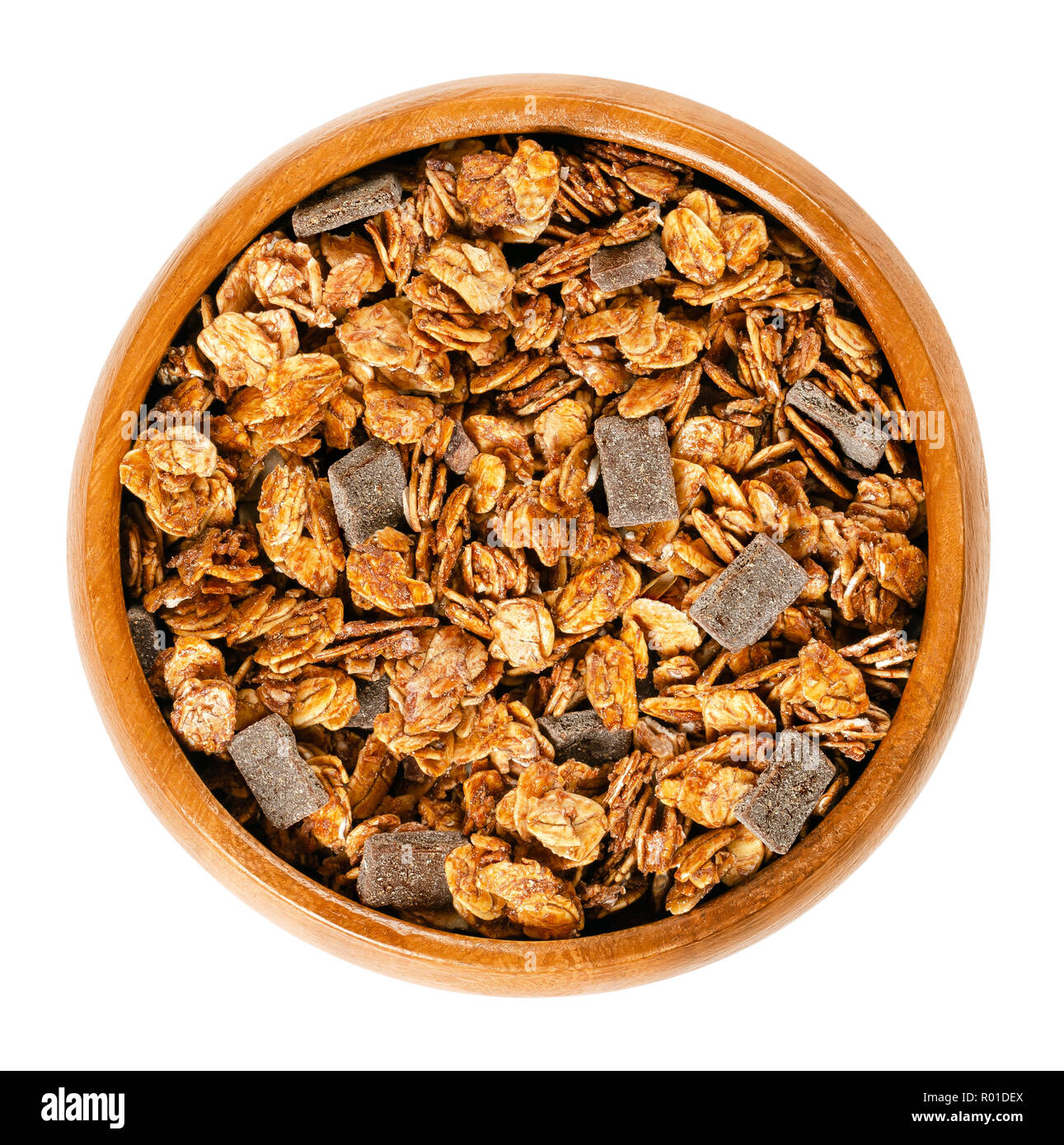 Crunchy chocolate granola in wooden bowl. Crispy cereals, made of rolled and toasted whole grain oat flakes, date juice and dark chocolate chunks. Stock Photo