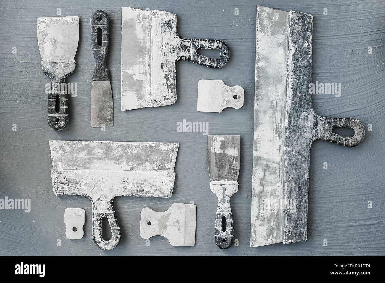 Kit of putty knives. Spatulas with the remaining mortar. Gastarbeiter or guest worker concept. Handyman. Tools for repair. Stock Photo