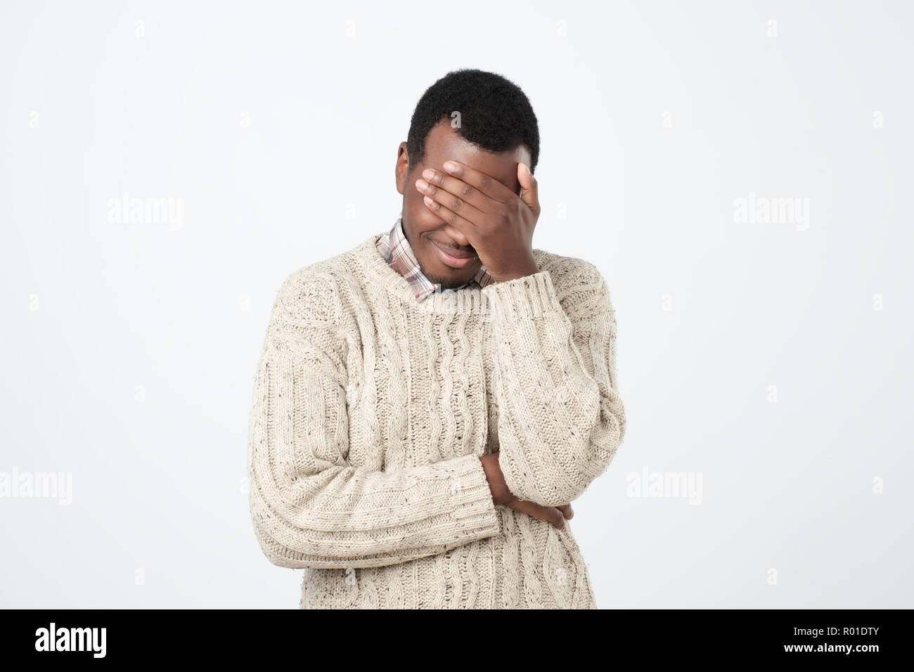 Unhappy african man covering his eyes by hand over gray background ...