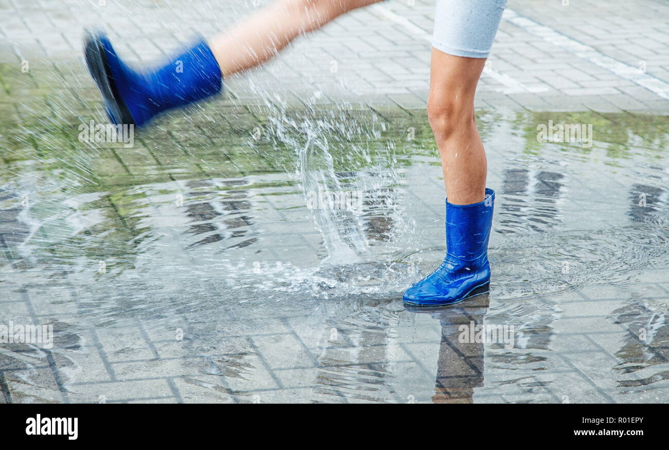 girl in blue rubber boots jumping in a 