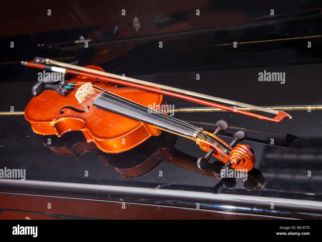 brown vintage violin with bow lying on a piano closeup indoor Stock Photo
