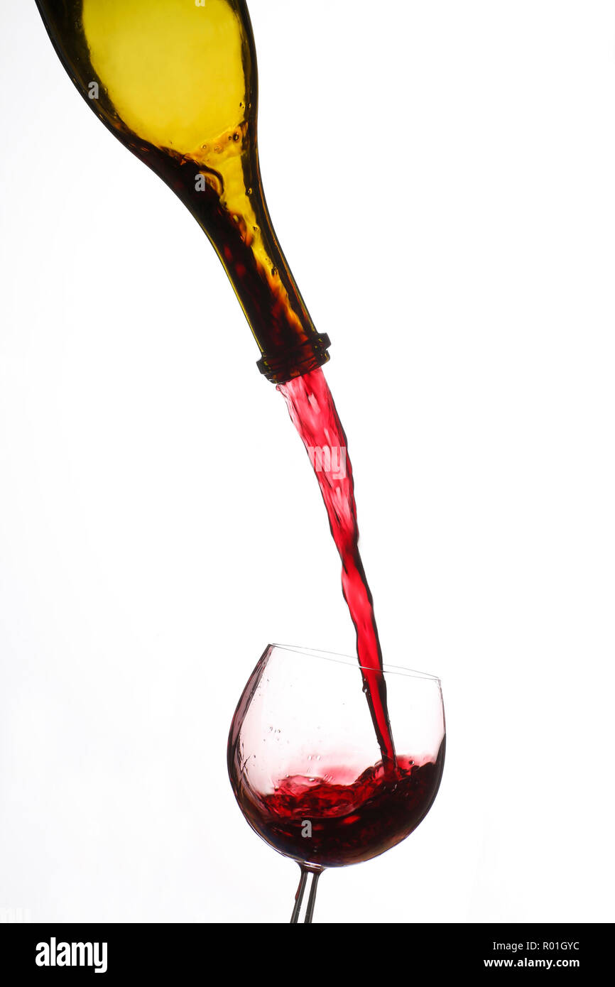 Red wine is poured from wine bottle into wine glass, cutout, Germany Stock Photo