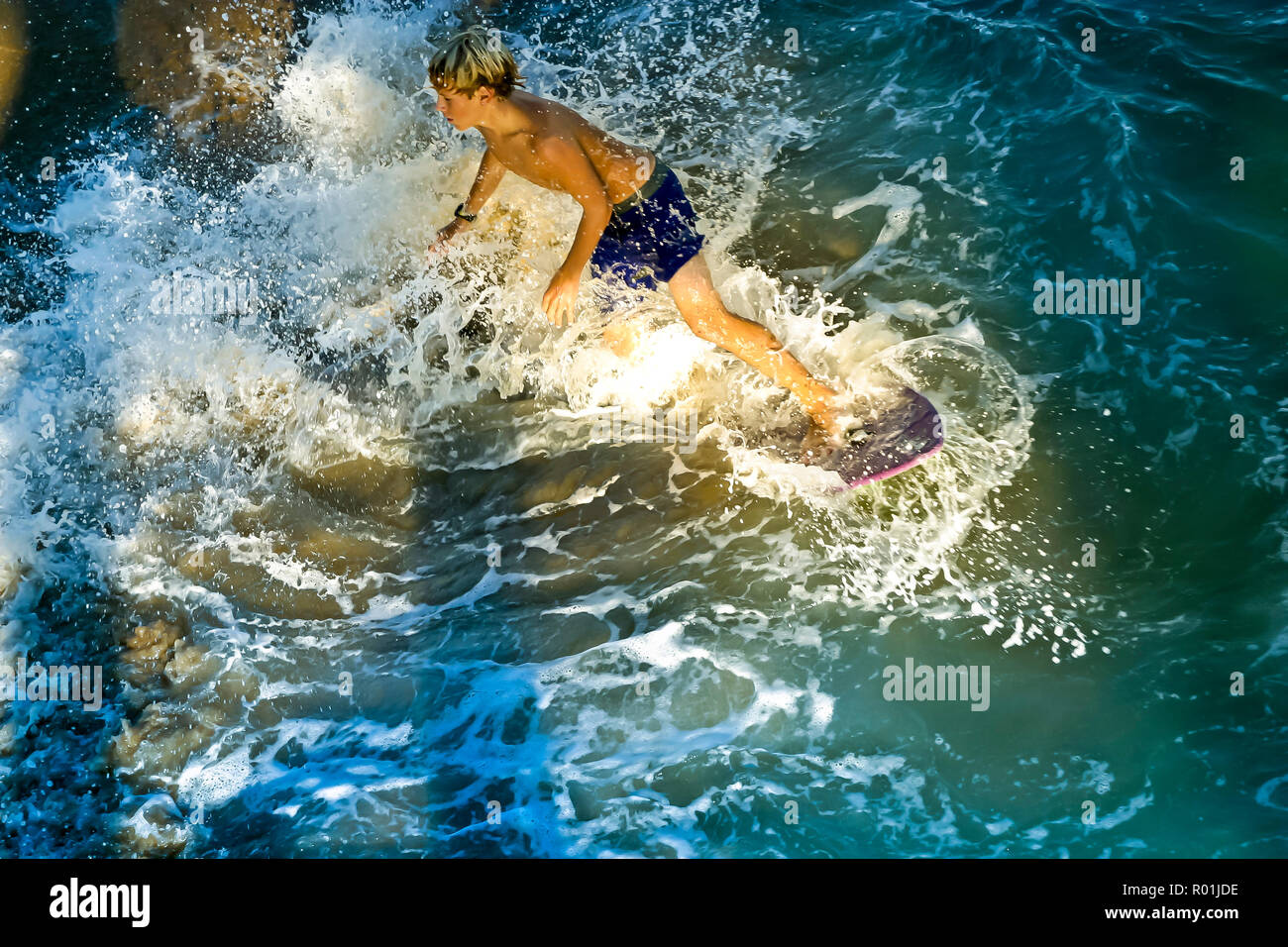 Young boy surfing on ocean waves at sunset.     © Myrleen Pearson .......Ferguson Cate Stock Photo