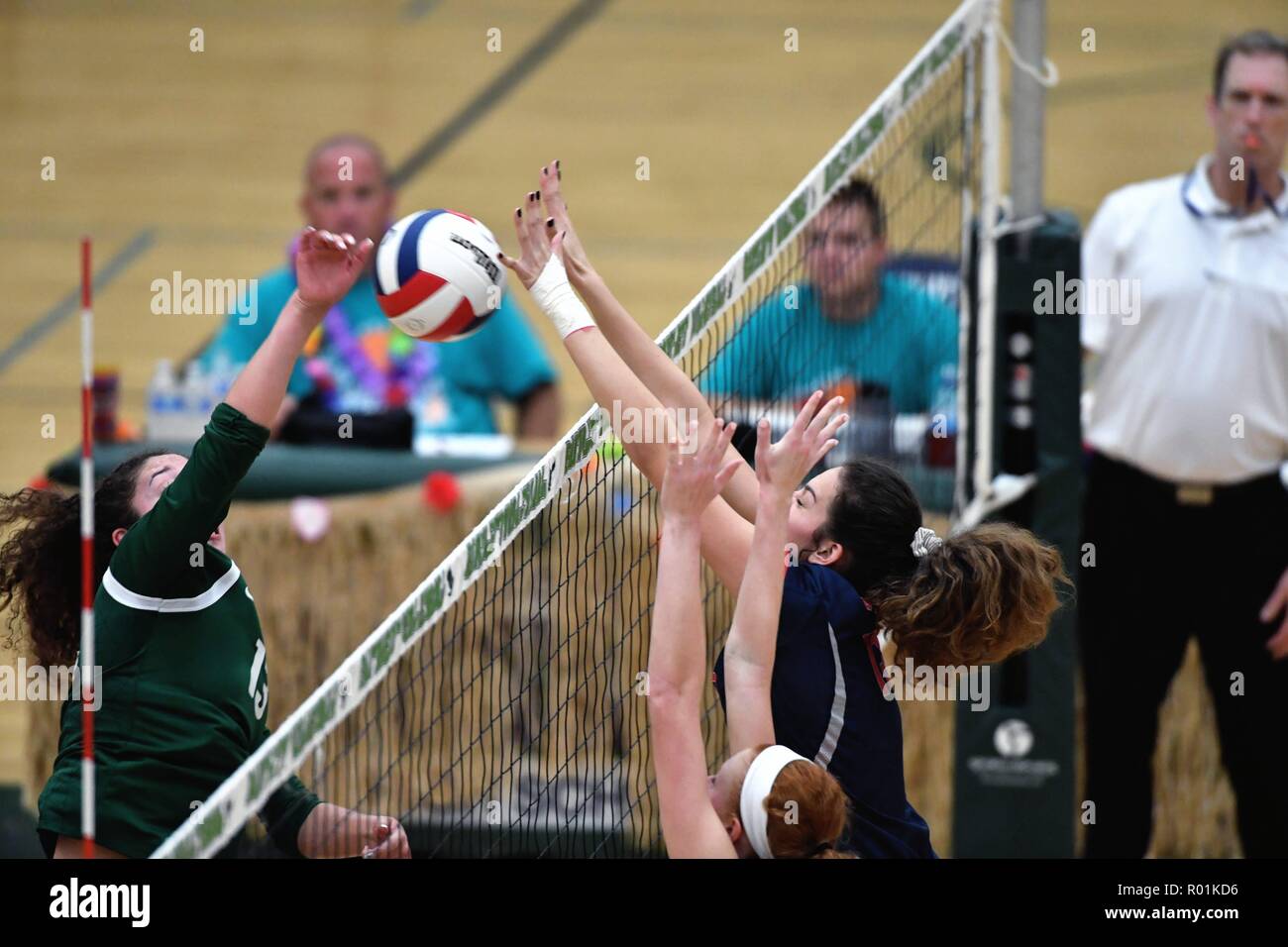 Player, at left, having her kill shot blocked at the net by a pair of opposing elevated players. USA. Stock Photo