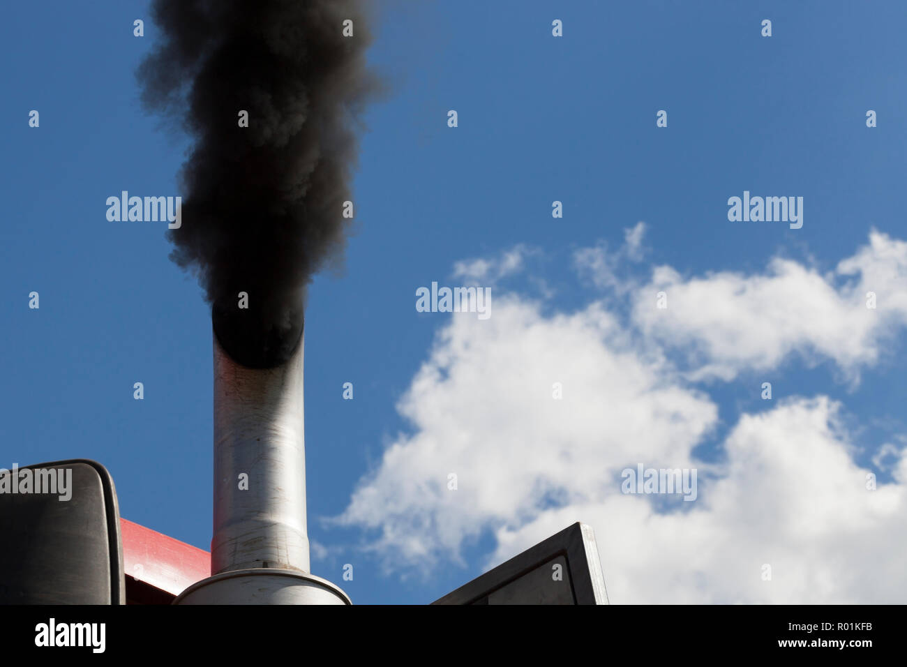 black smoke against the blue sky coming from the exhaust pipe of the ...