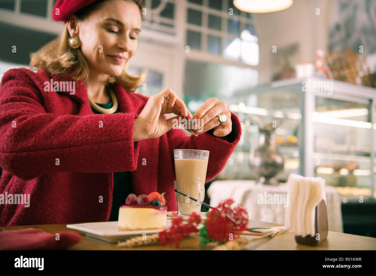Stylish elegant French woman adding some sugar in her latte Stock Photo