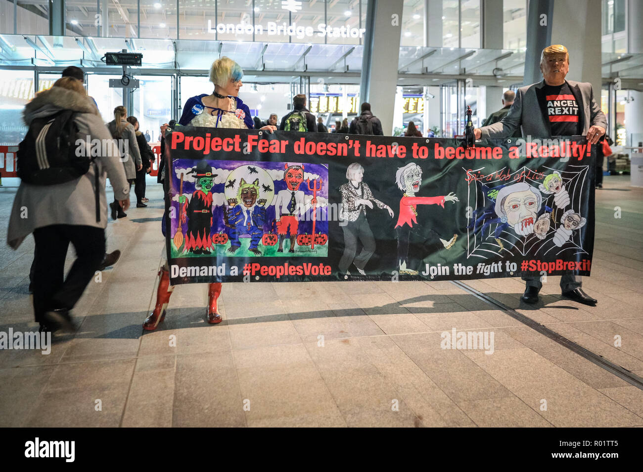 London Bridge Station, London, UK, 31st Oct 2018. Activist and writer Madeleina Kay (l) , and Joan (r) , a protester with Donald Trump mask and 'chlorinated chicken' puppet, take their banner around London Bridge Station to raise awareness amongst the busy evening commuter crowd. Activists from anti-Brexit group 'No 10 Vigil' protest outside London Bridge Station with placards, banners and music. and hand out leaflets. Credit: Imageplotter News and Sports/Alamy Live News Stock Photo