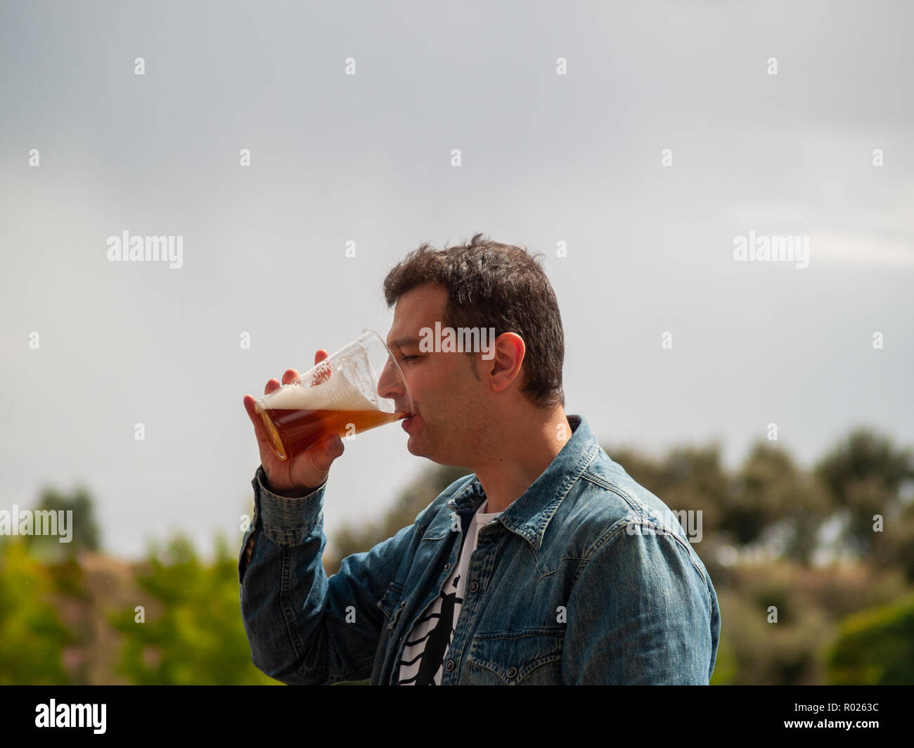 A man drinking beer at an outdoor celebration Stock Photo Alamy