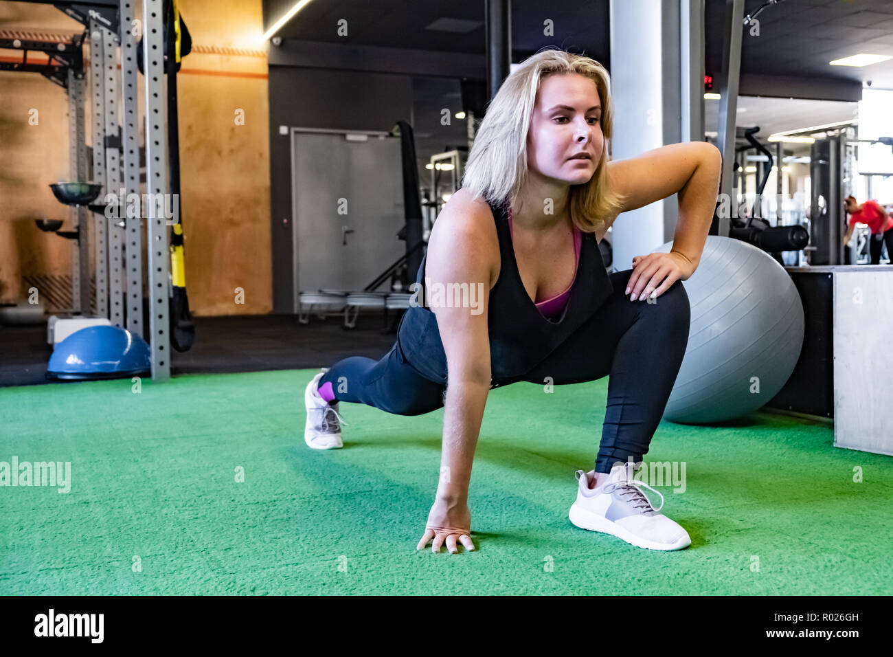 Young fit woman at the gym doing stationary lunge exercise. Female athlete at a fitness room working out on walking lunge exercise Stock Photo