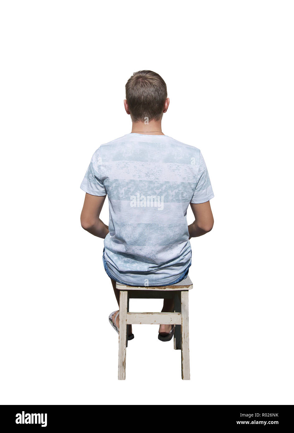 Rear view full length portrait of pensive young man sitting on a old chair and meditate isolated over white background. Stock Photo