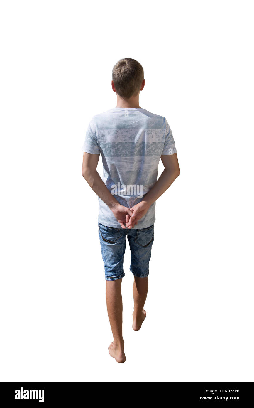 Rear view full length portrait of young man walking and stepping with hands behind his back isolated over white background. Stock Photo