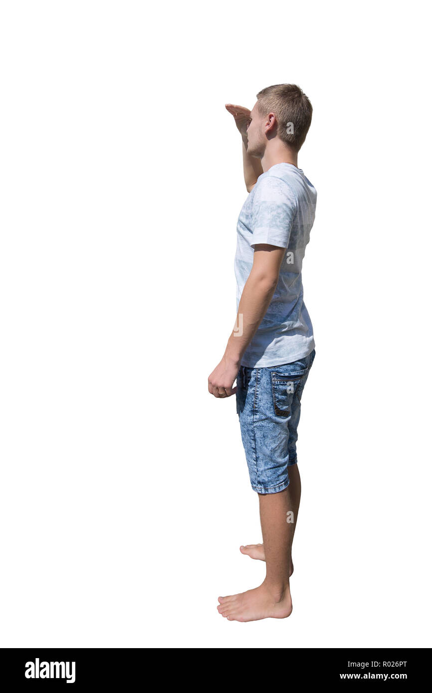 Side view full length portrait of casual young man holding hand to forehead over eyes to protect from sun rays, searching or looking for someone isola Stock Photo