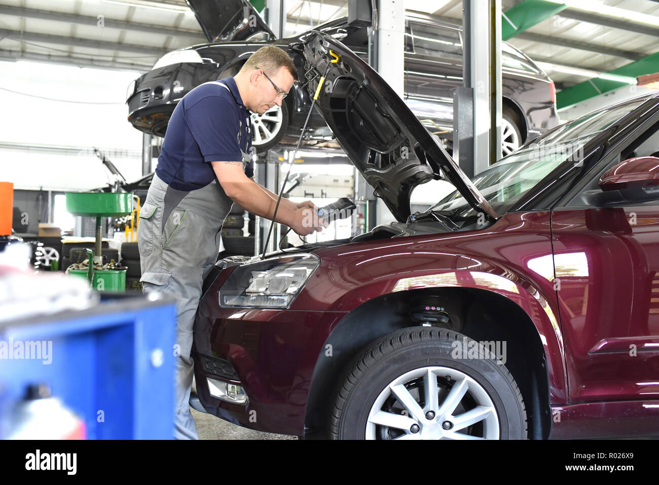 car mechanic in a workshop - engine repair and diagnosis on a vehicle Stock Photo