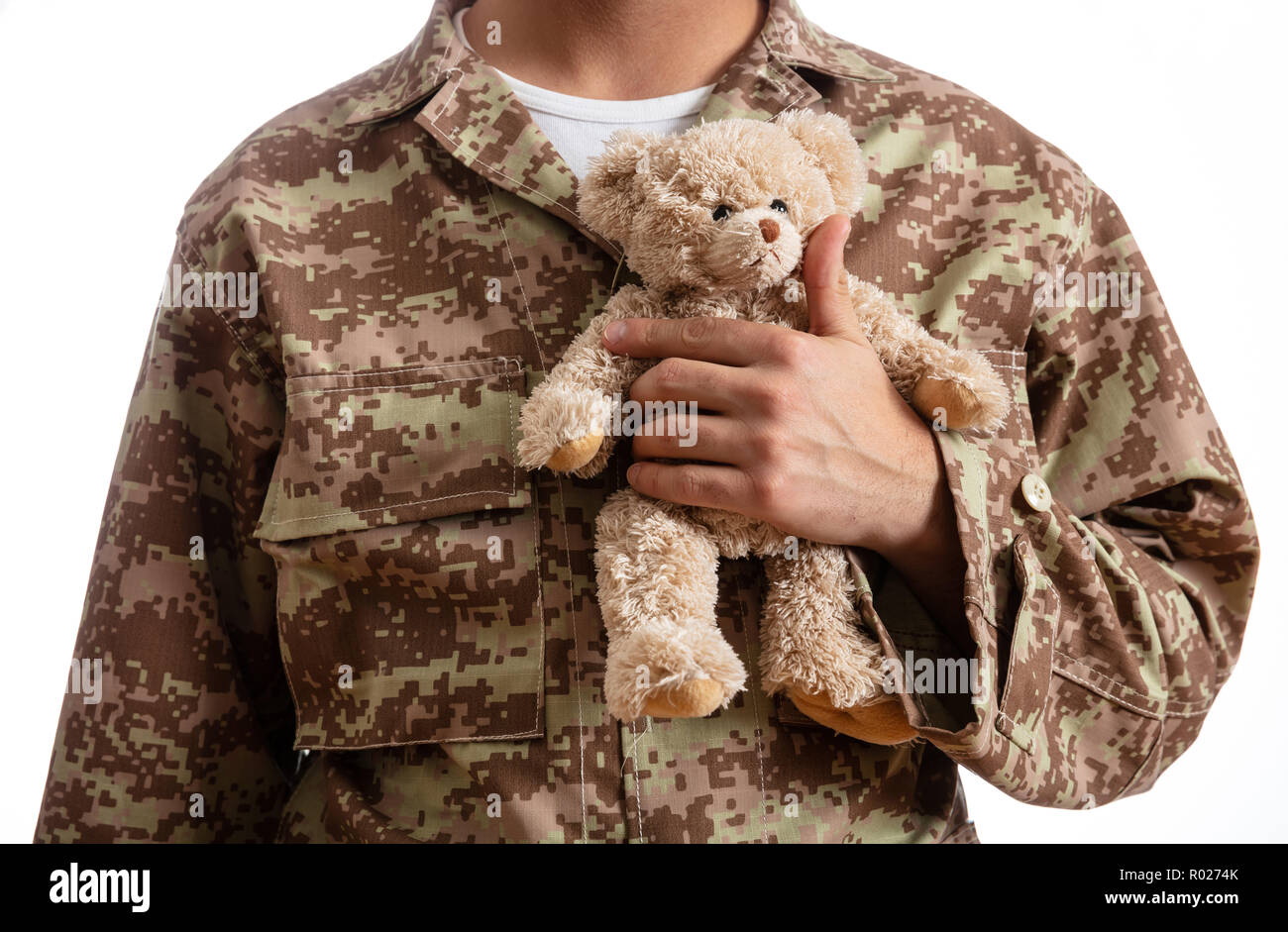 Father in the Army. Young soldier holding a teddy bear standing on white background Stock Photo