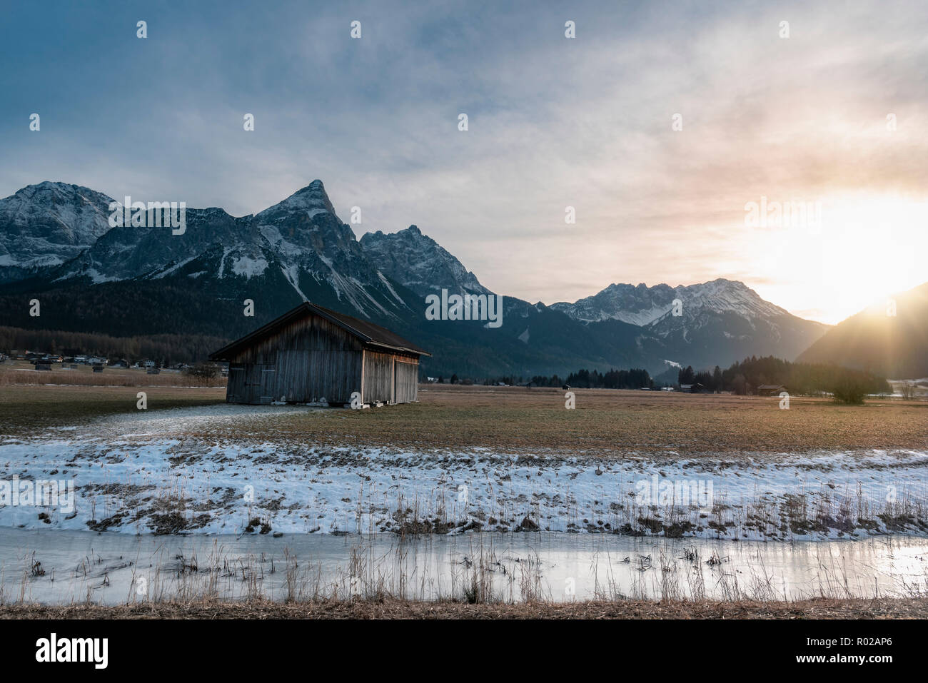 Winter Alpine Landscape With A Wooden Cabin A Frozen River And