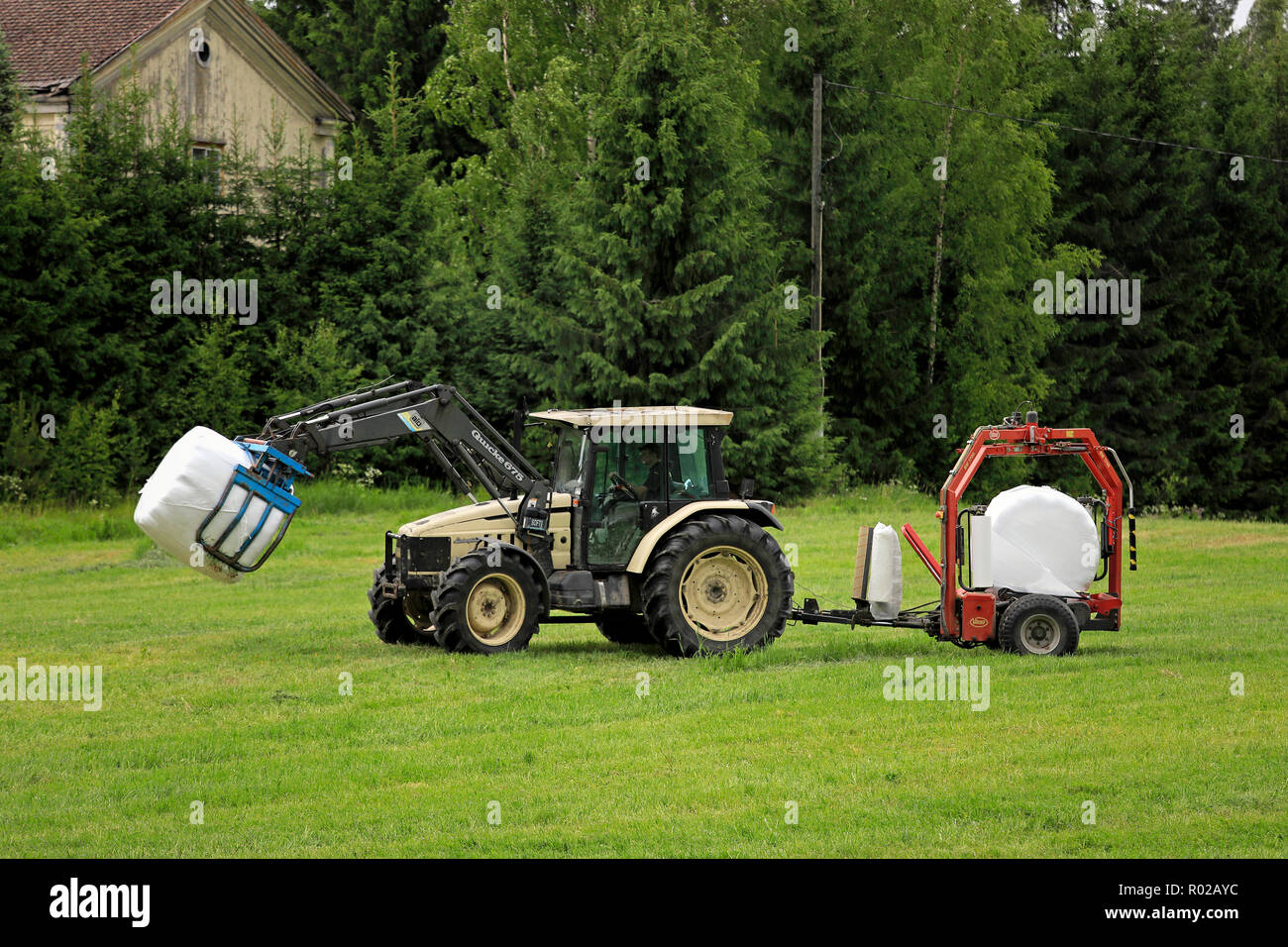 Uurainen, Finland - June 15, 2018: Farmer hauls wrapped hay bales with Quicke front end loader on Lamborghini tractor and Vicon BV 1700 wrapper. Stock Photo