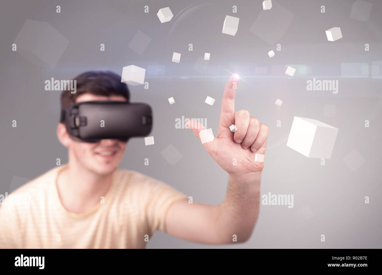 Young impressed man wearing virtual reality goggles with grey cubes ...