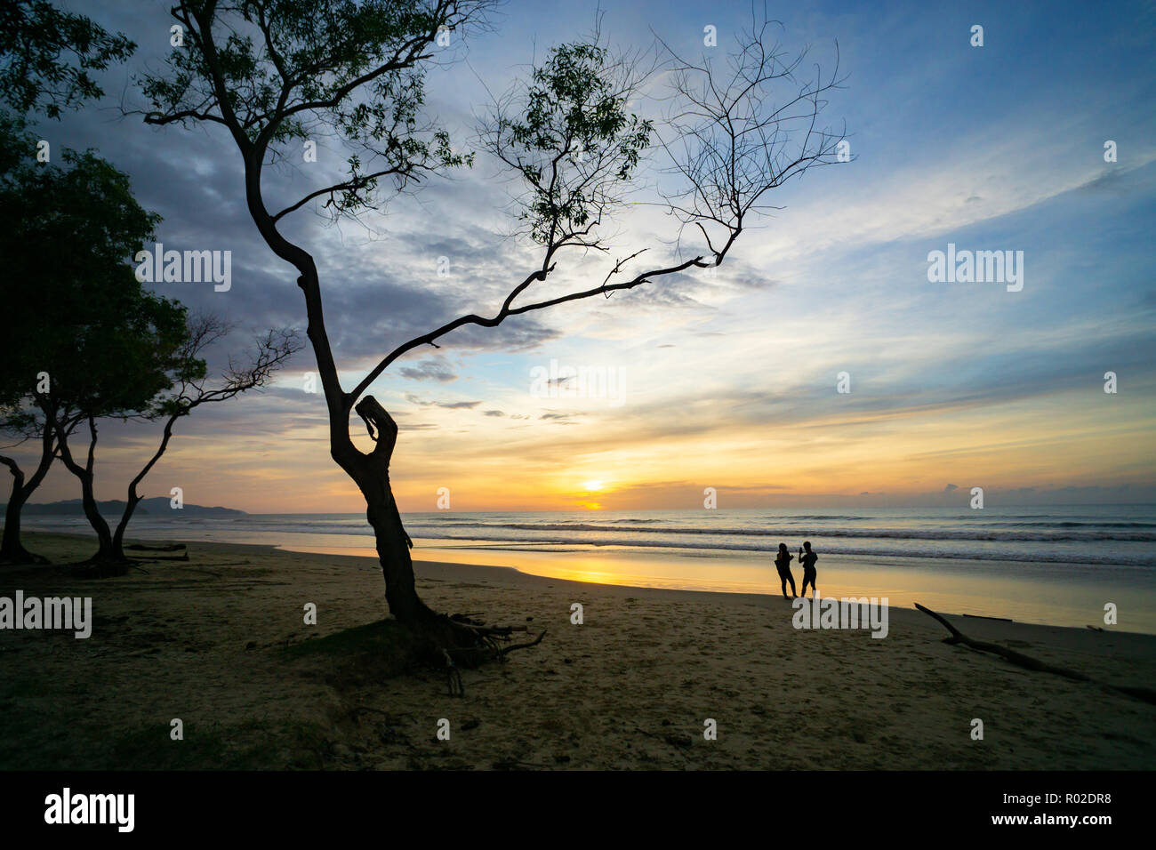 Beautiful sunset at the beach with couple silhouette Stock Photo - Alamy