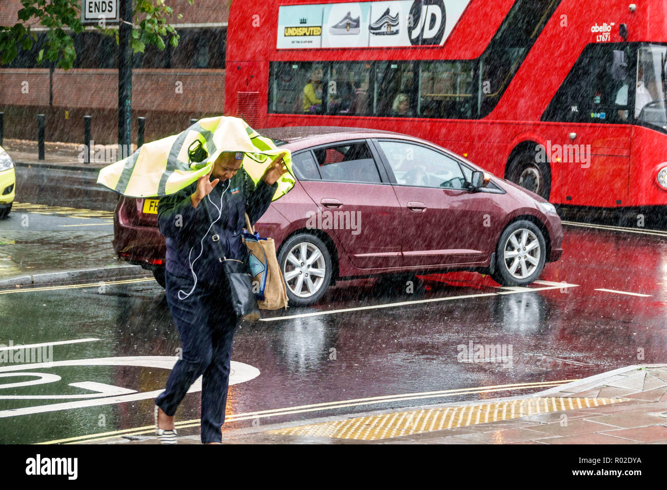 London England,UK,Lambeth South Bank,raining,rainy weather,wet pavement,pedestrian crossing,traffic,Black woman female women,covering head,UK GB Engli Stock Photo