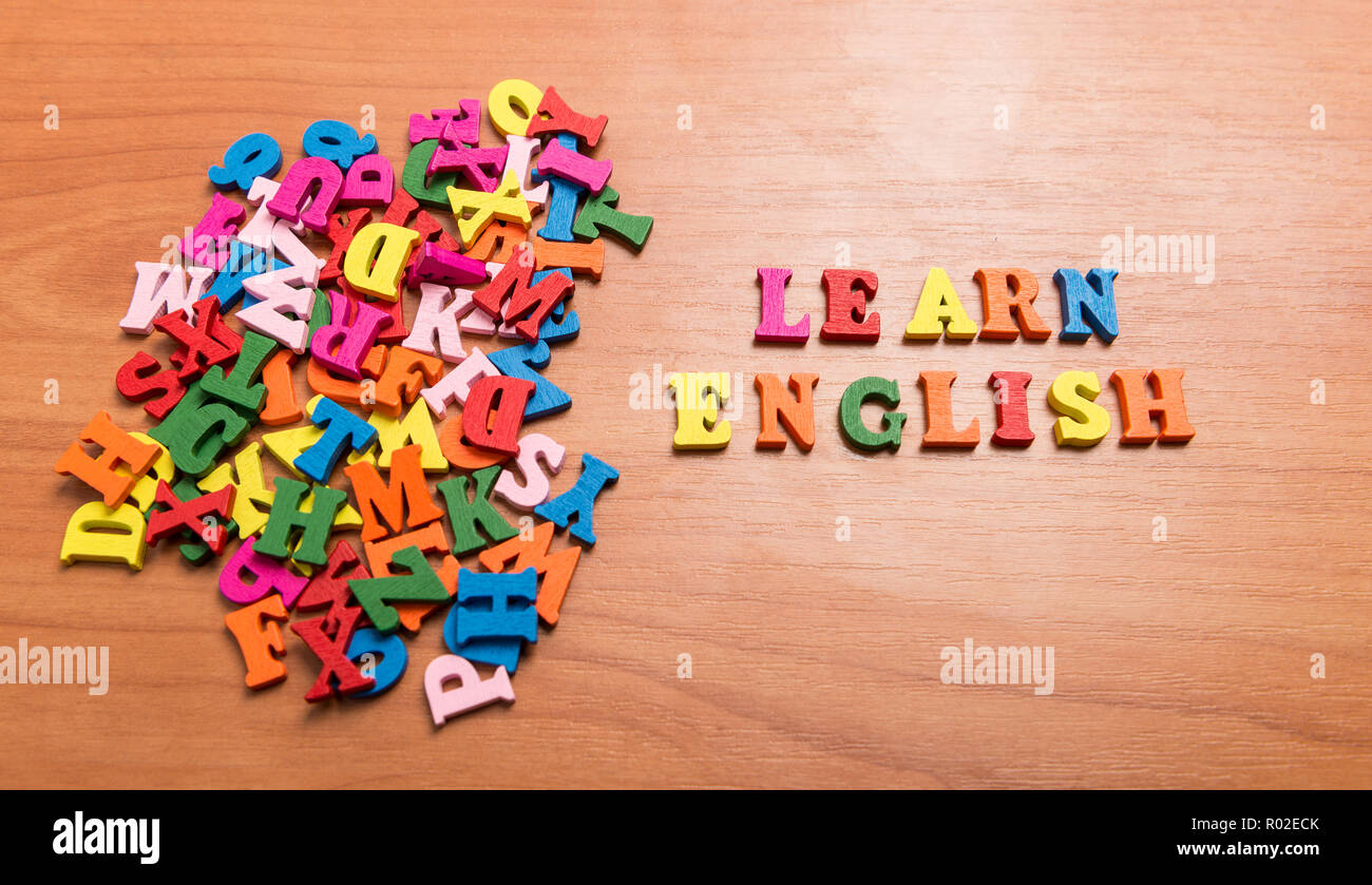 Learn English message in wooden letters near a pile of other letters over office table background Stock Photo